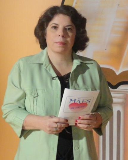 Uma mulher com uma jaqueta verde está segurando um pedaço de papel que diz mais