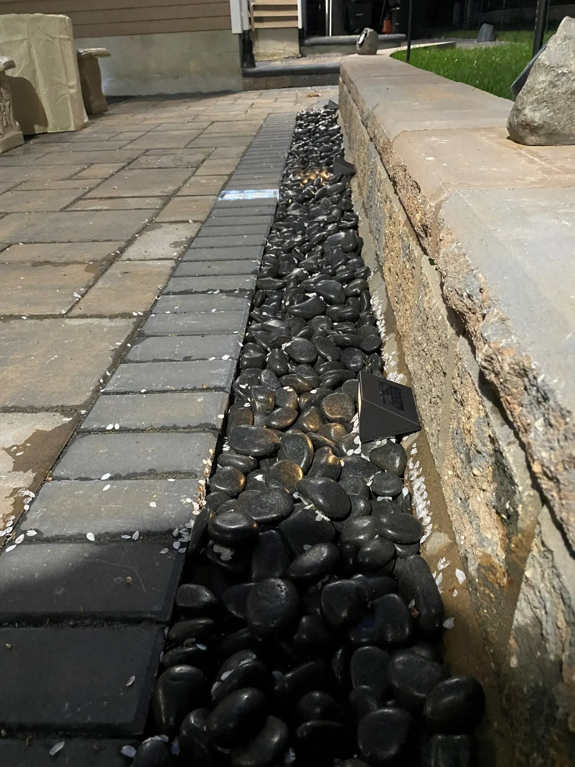 A sidewalk with black rocks on the side of it