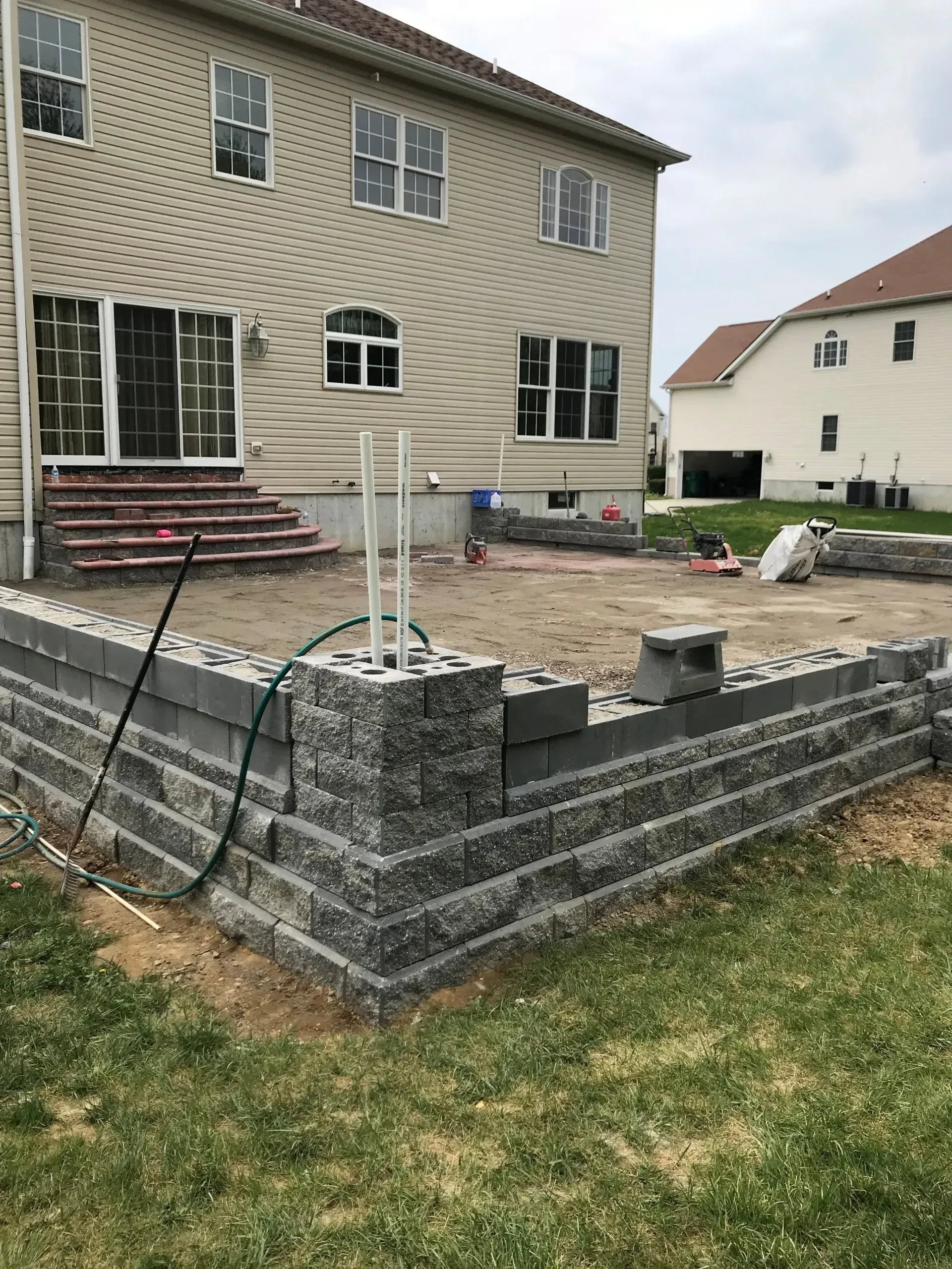 A brick wall is being built in the backyard of a house.