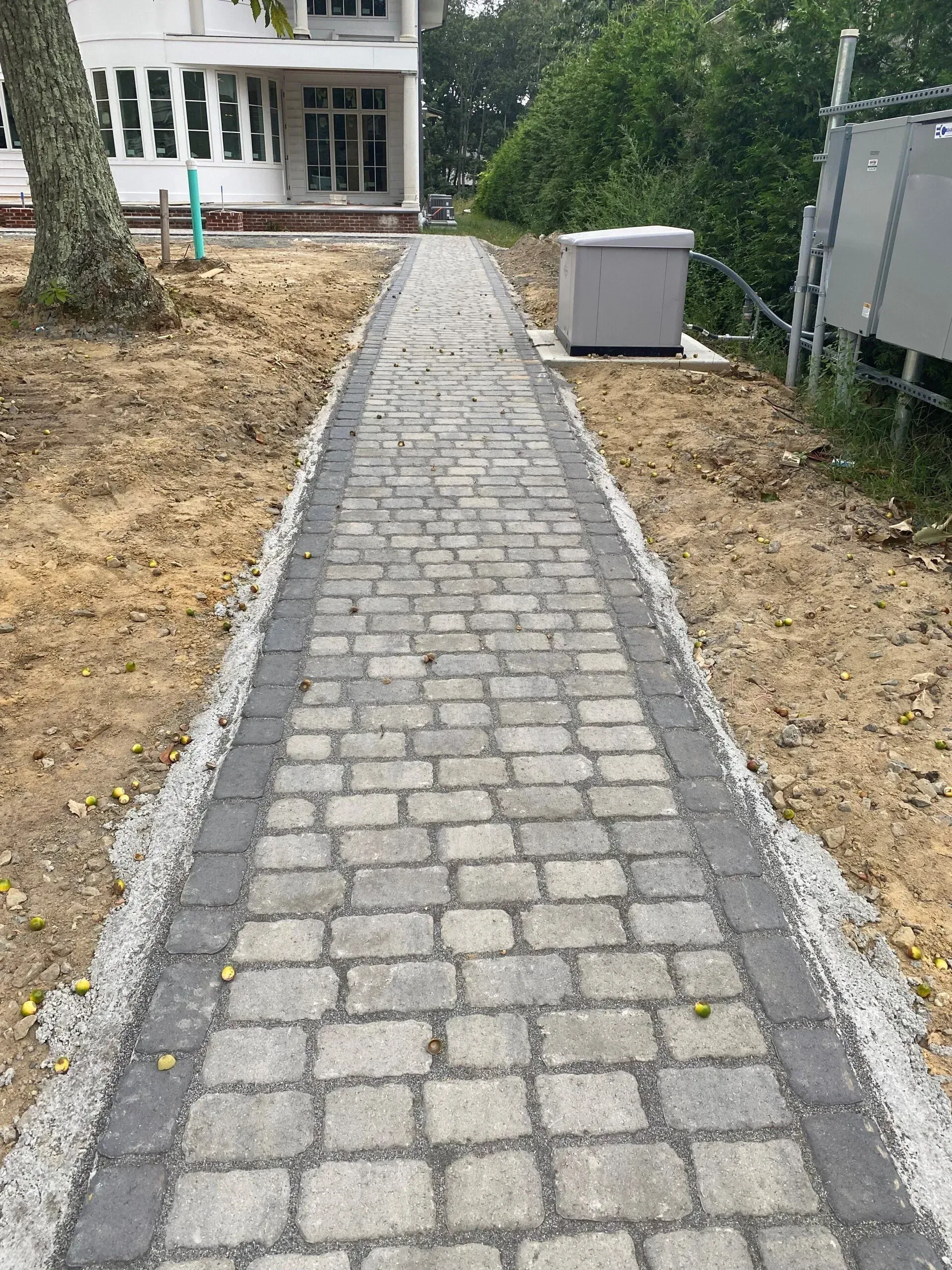 A brick walkway leading to a white house