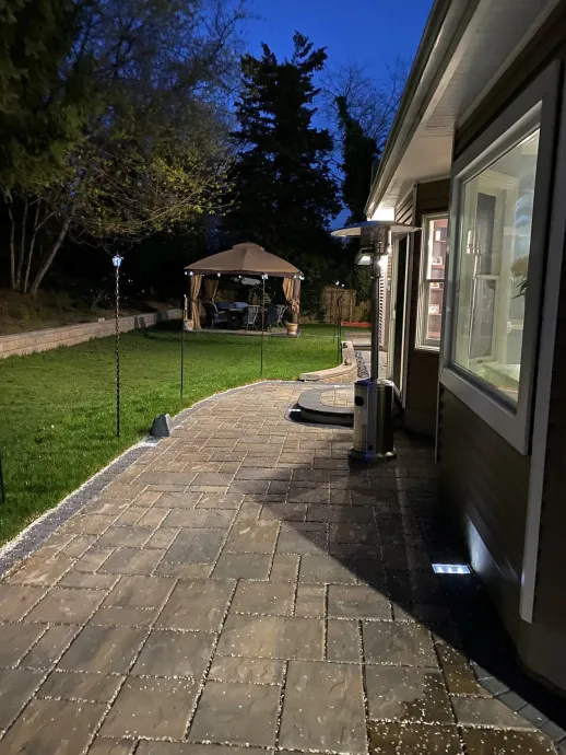A house with a gazebo in the backyard at night.
