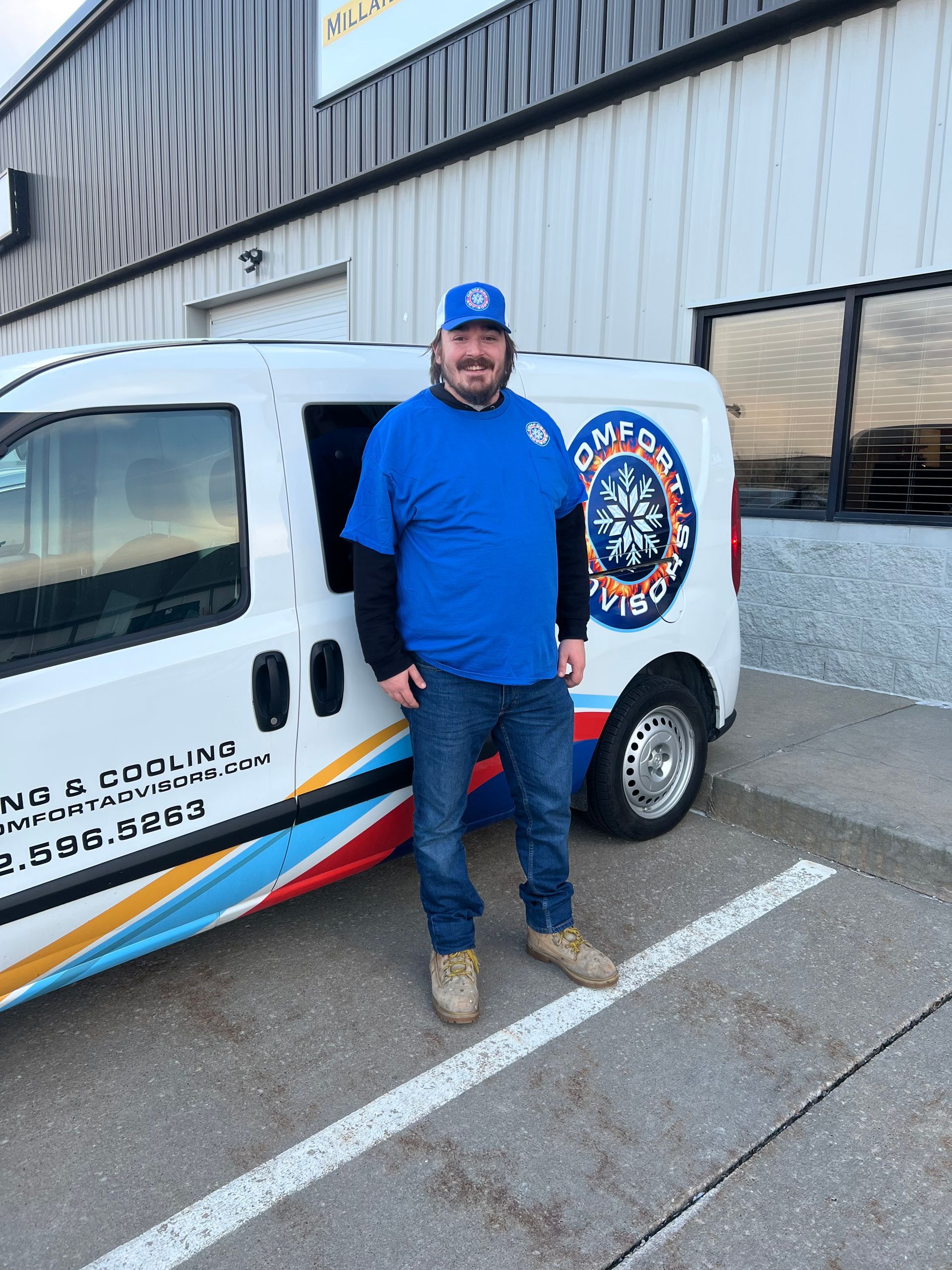 Man in blue shirt and cap stands by a white van with 