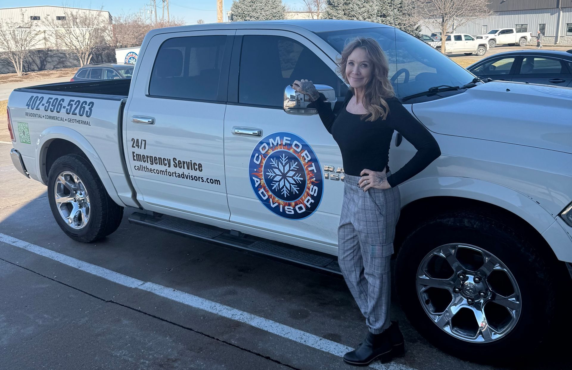 Woman stands by a white Comfort Solutions truck, smiling. The truck has company logo and phone number.