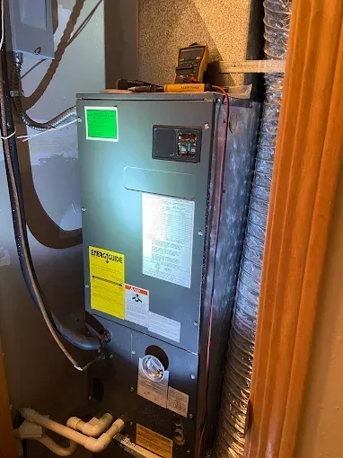 Furnace unit in a utility room with electrical wiring and a digital multimeter on top.