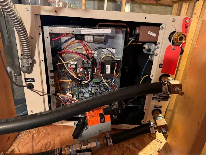 Open view of a mechanical unit, wires and components visible. Black insulated pipes cross the frame.