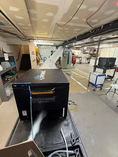 A black Thermoseal machine expelling mist, inside an industrial setting, with a person in the background.