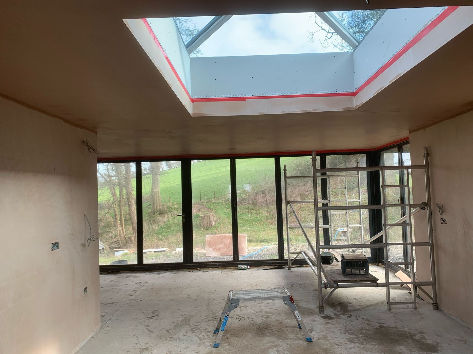A room with a ladder and a skylight in the ceiling.