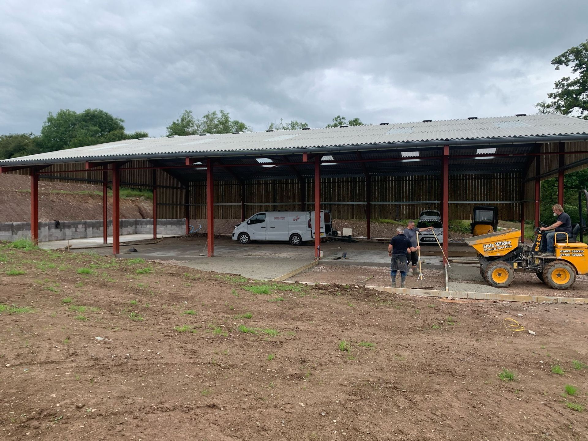A man is driving a bulldozer in front of a building under construction.