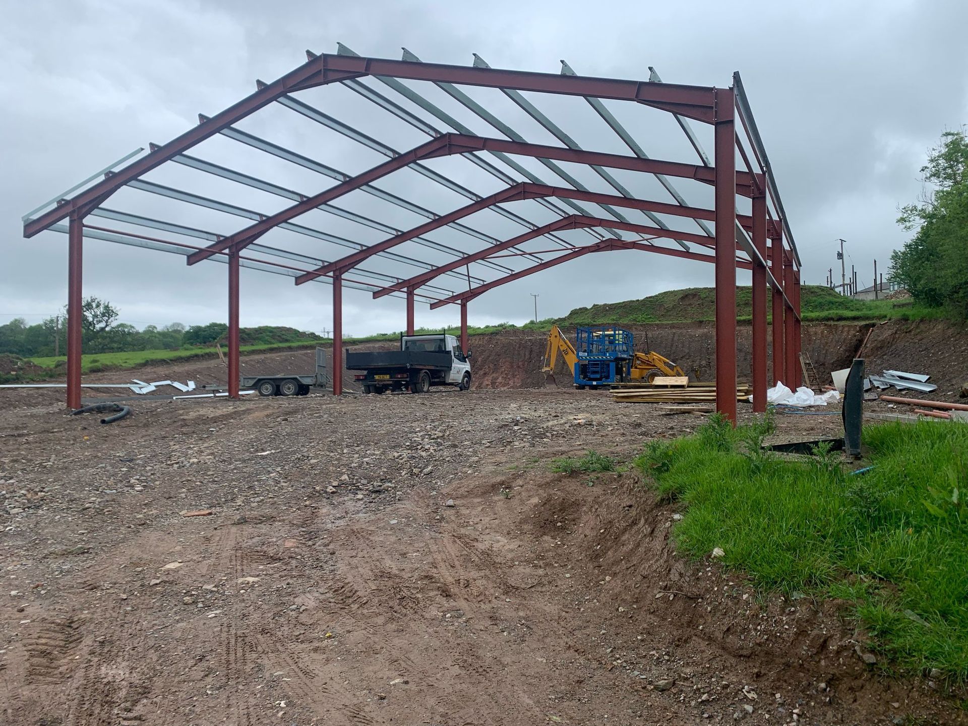 A large metal structure is being built in a dirt field.