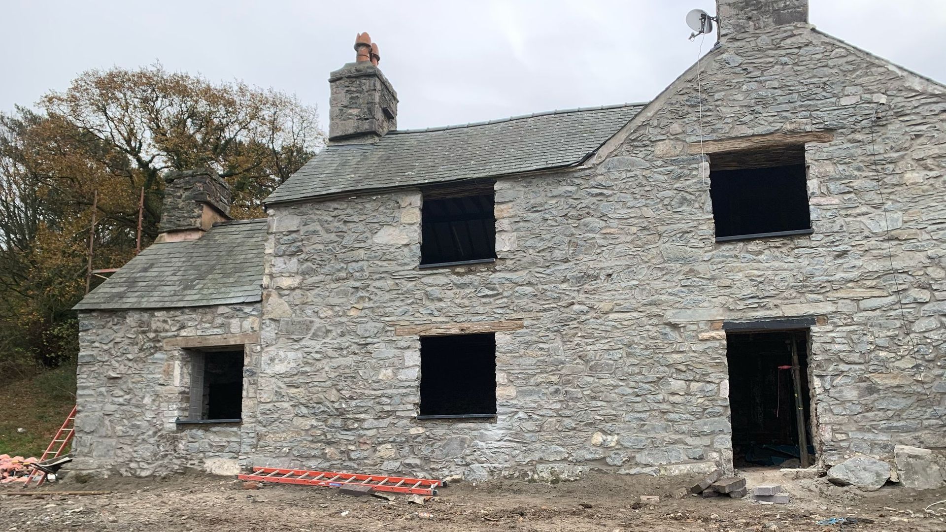 A large stone house is being built in a dirt field.