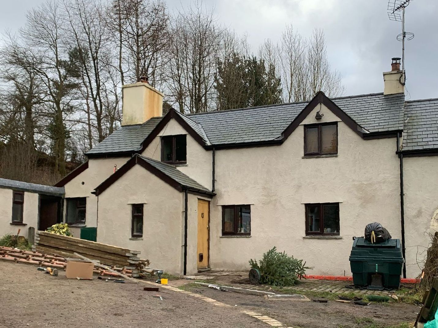 A large white house with a slate roof is surrounded by trees.