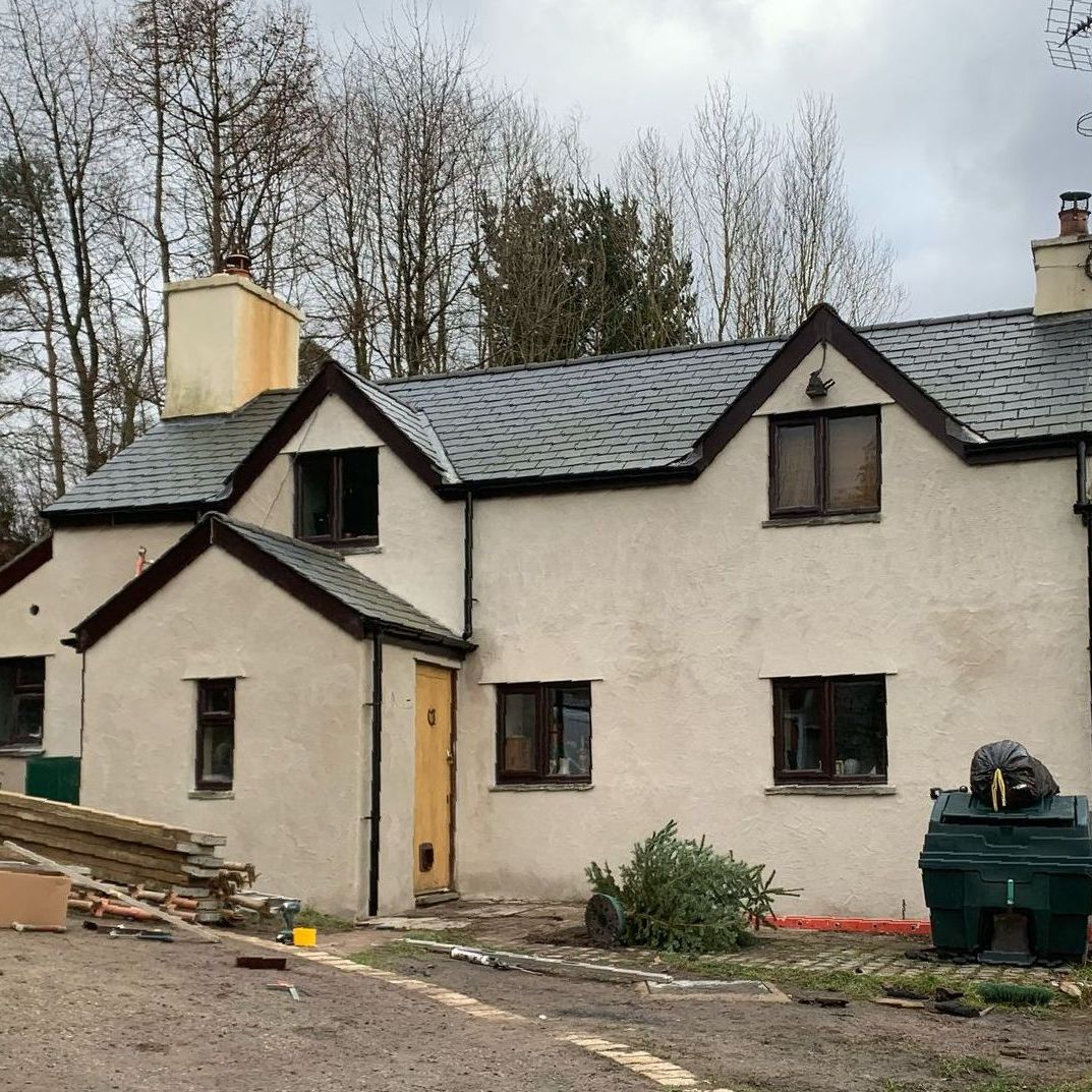 A white house with a black roof and a chimney