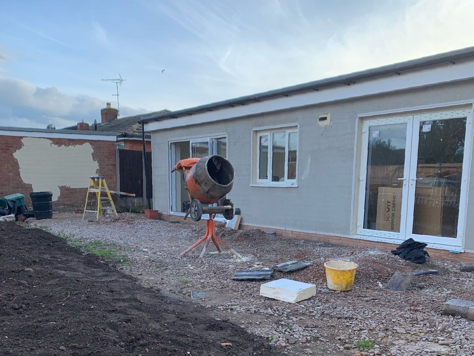 A house is being built with a cement mixer in front of it.