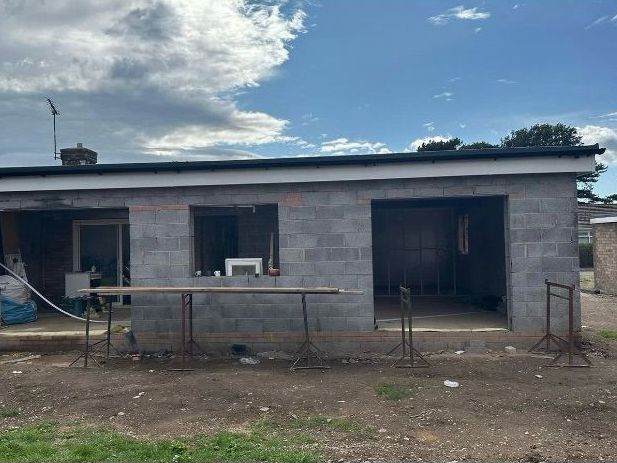 A small brick house is being built with a table in front of it.