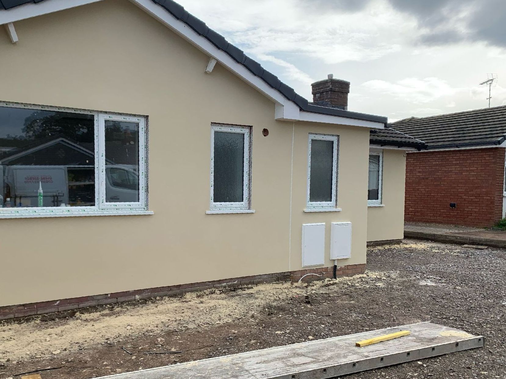 A house with a lot of windows is being built in a residential area.