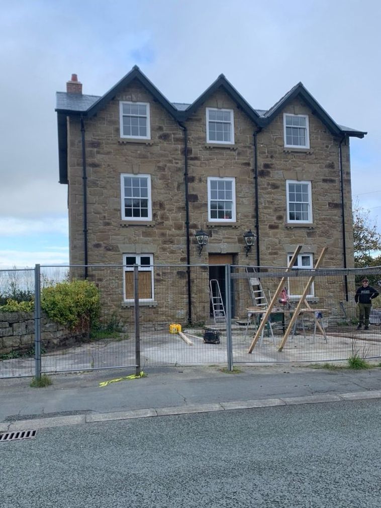 A large brick building with a fence around it is being remodeled.