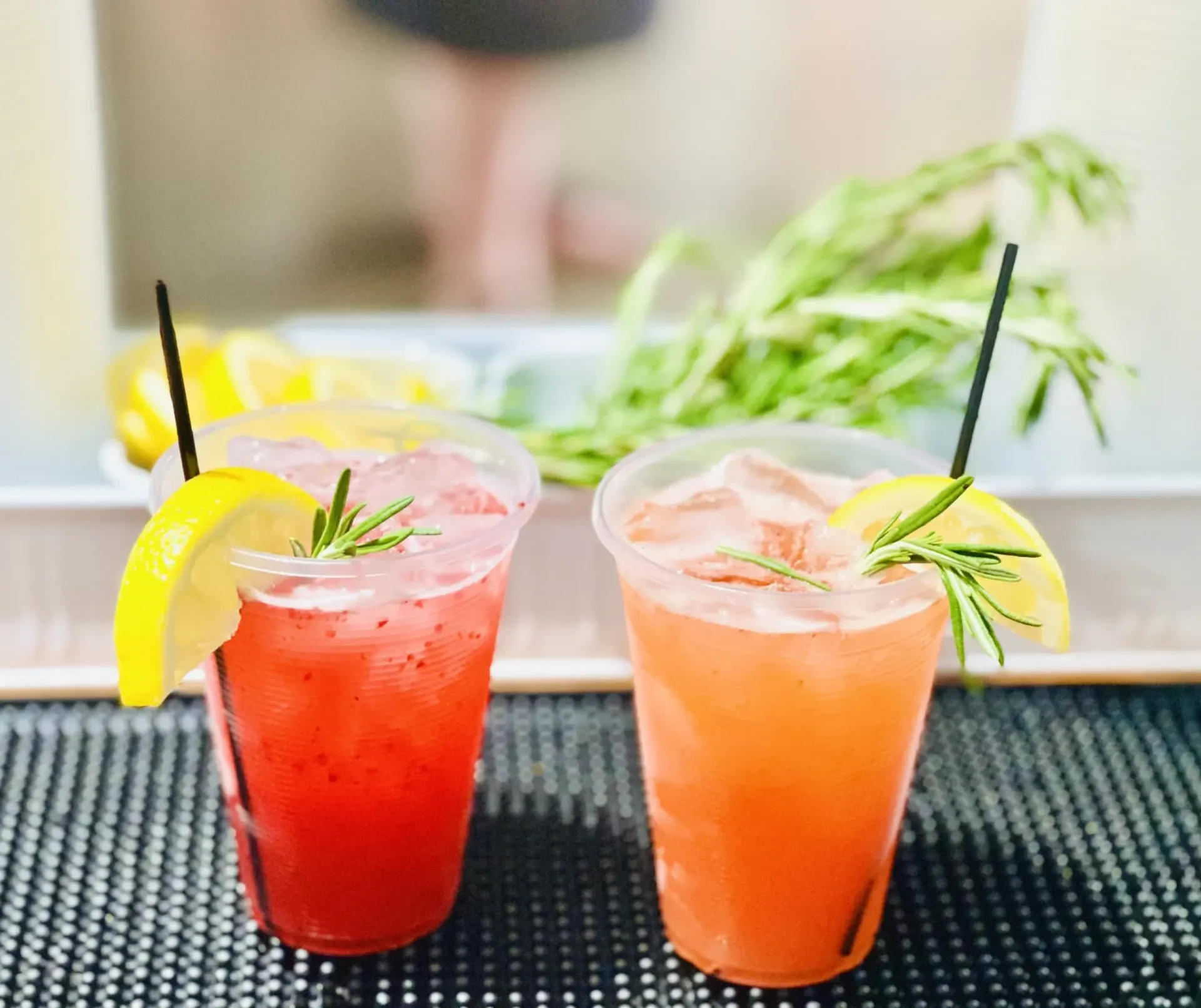 Two drinks in plastic cups with straws and lemon slices