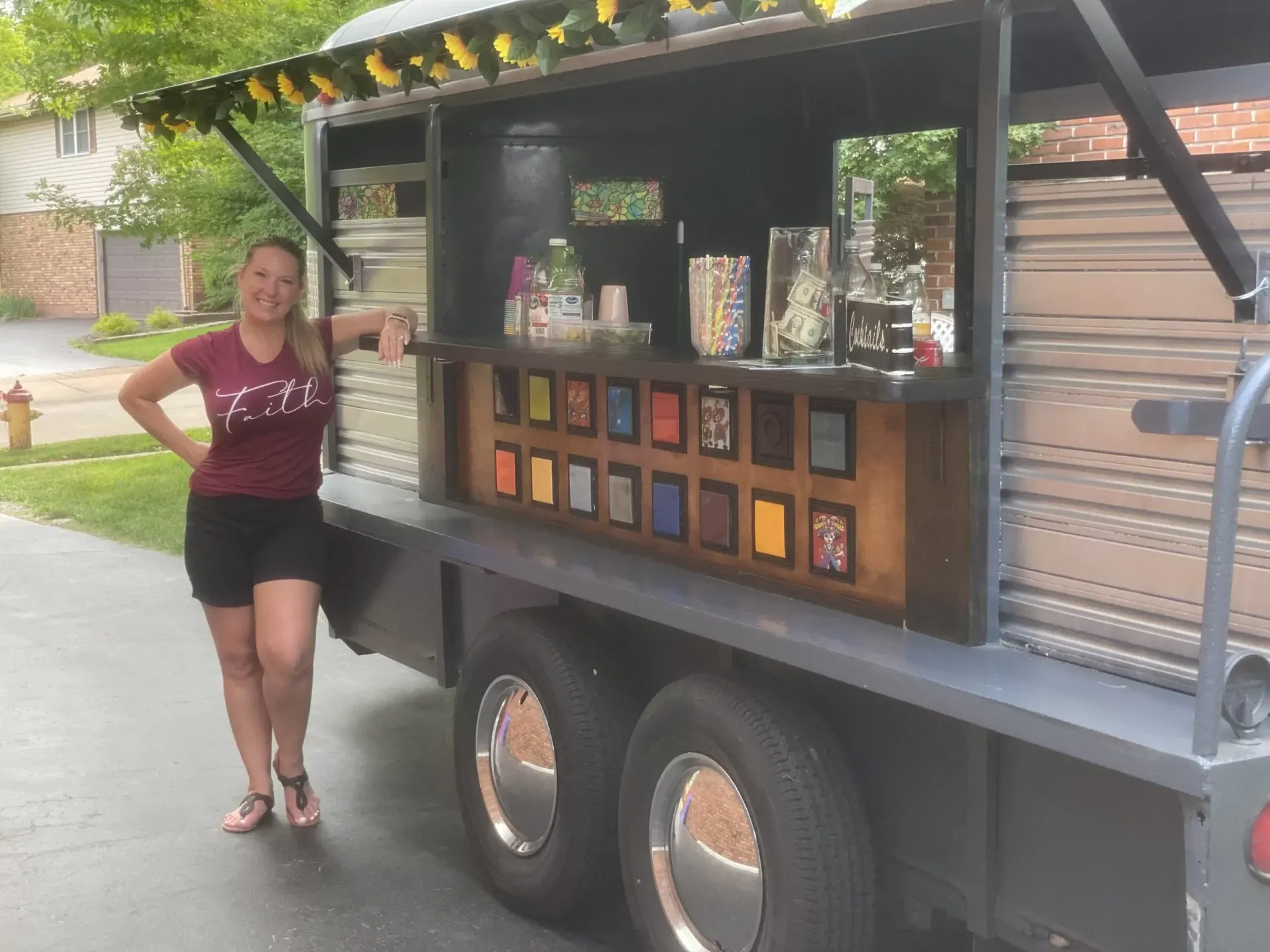 A woman in a red shirt is standing next to a food truck