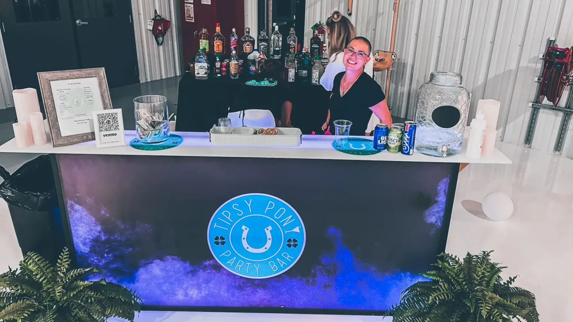 A woman is standing behind a bar talking on a cell phone.