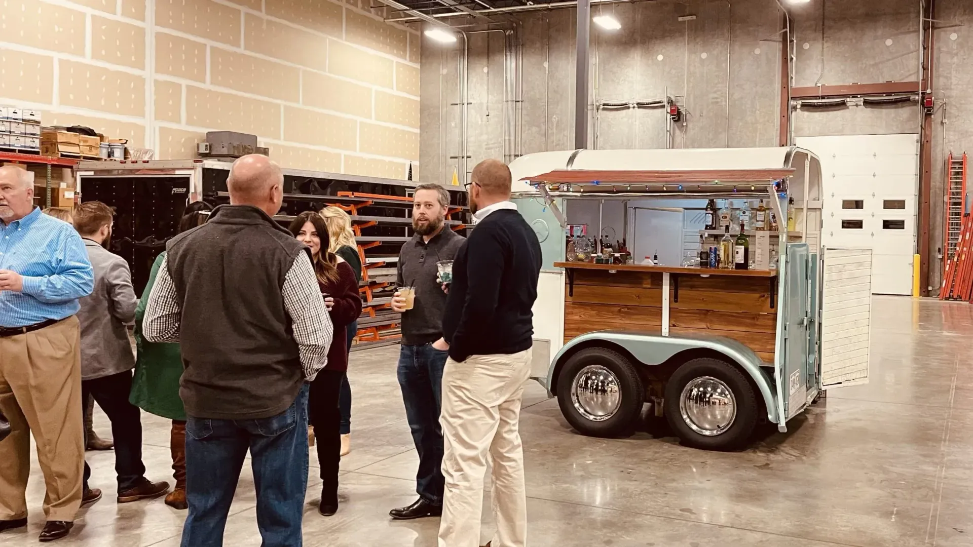 A group of people are standing around a trailer in a warehouse.
