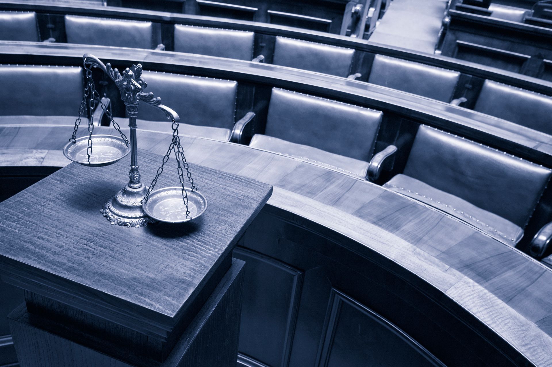 A scale of justice sits on a table in a courtroom