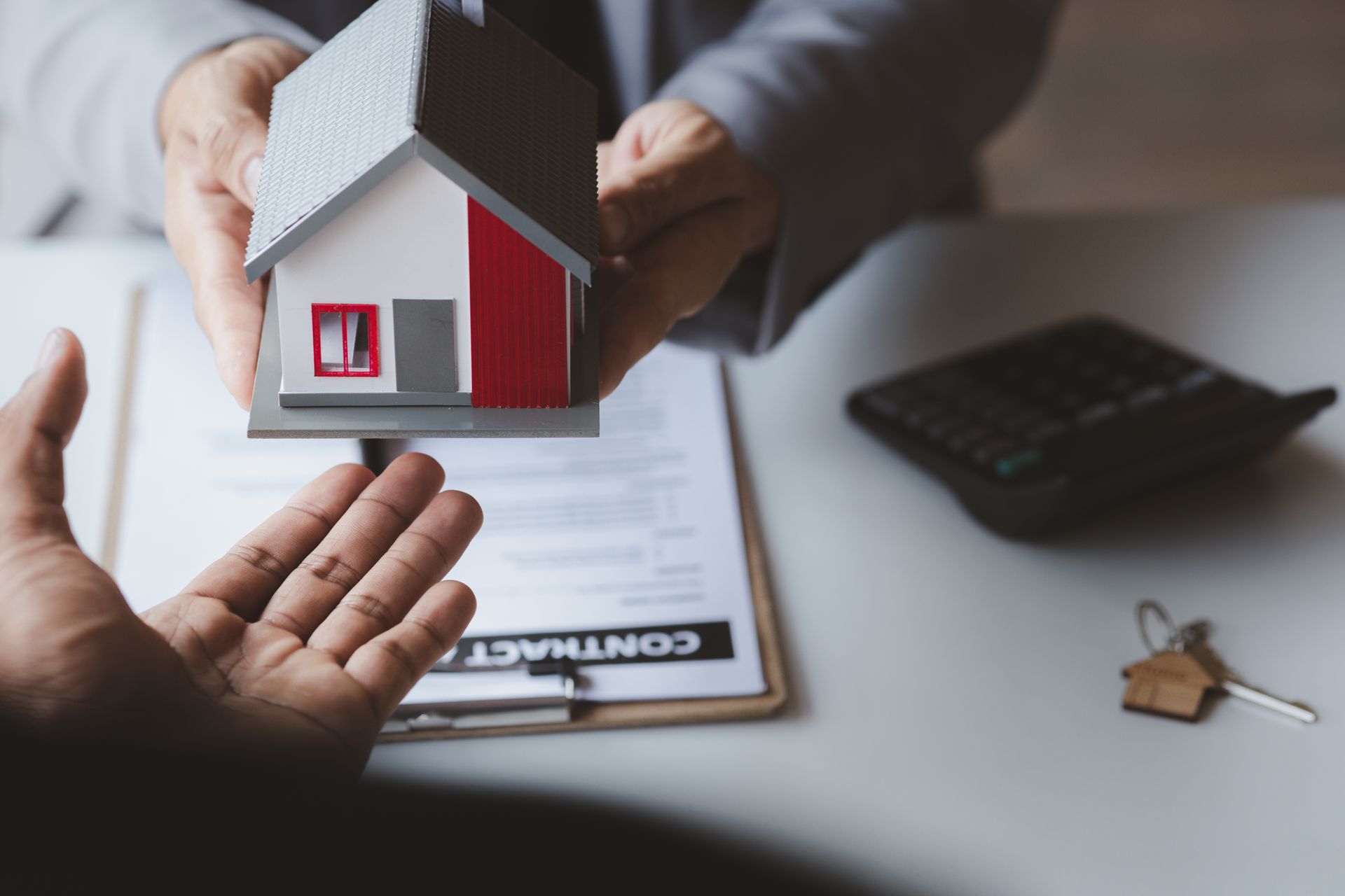 A person is holding a model house in their hand.