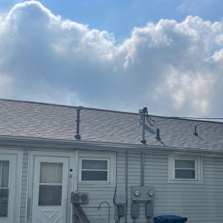 A white house with a roof and a blue sky with clouds in the background.