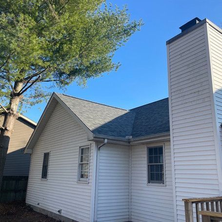 A white house with a gray roof and a chimney.