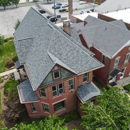 An aerial view of a large brick house with a gray roof.