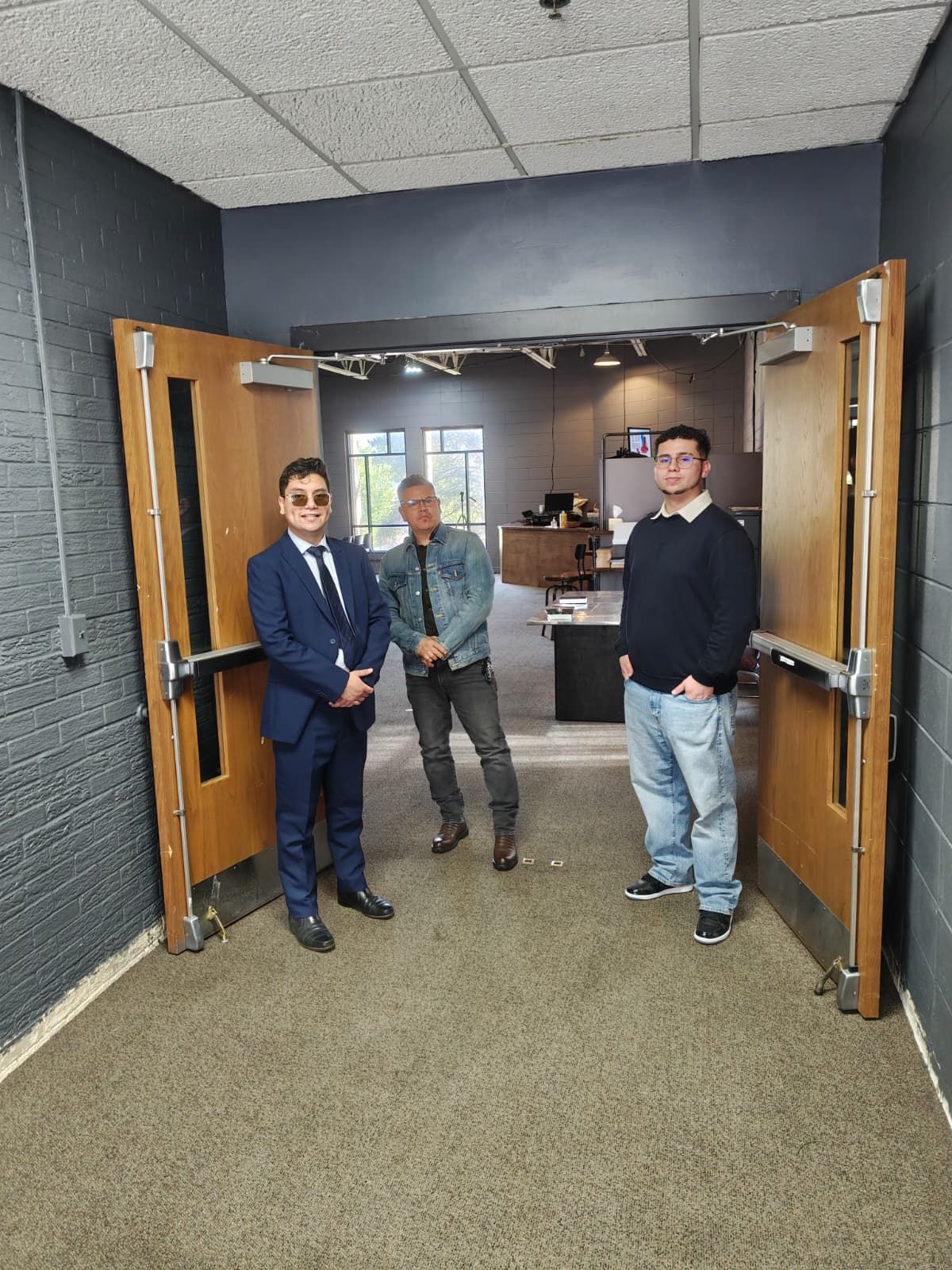 Group of people posing for a photo. Some are smiling in front of a Christmas tree and decorated backdrop.