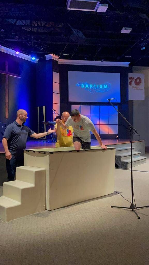 Man being baptized in a church. Two men, water baptism pool, blue lighting, stage, 