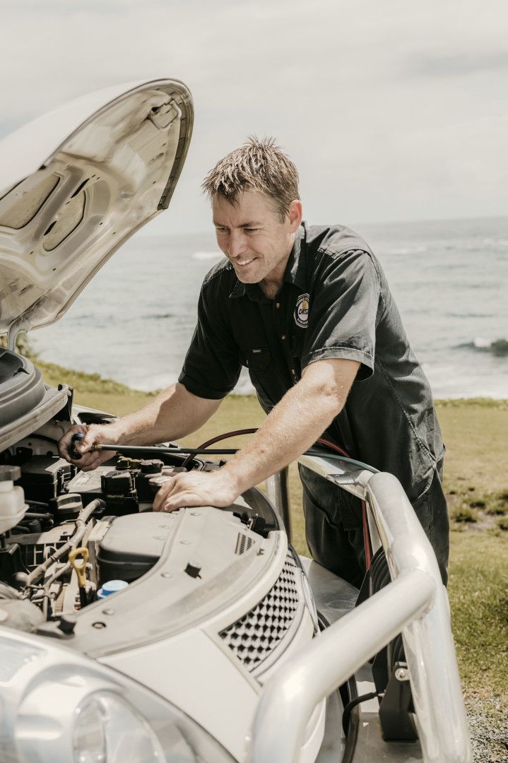 A man is working on the engine of a car with the hood open.