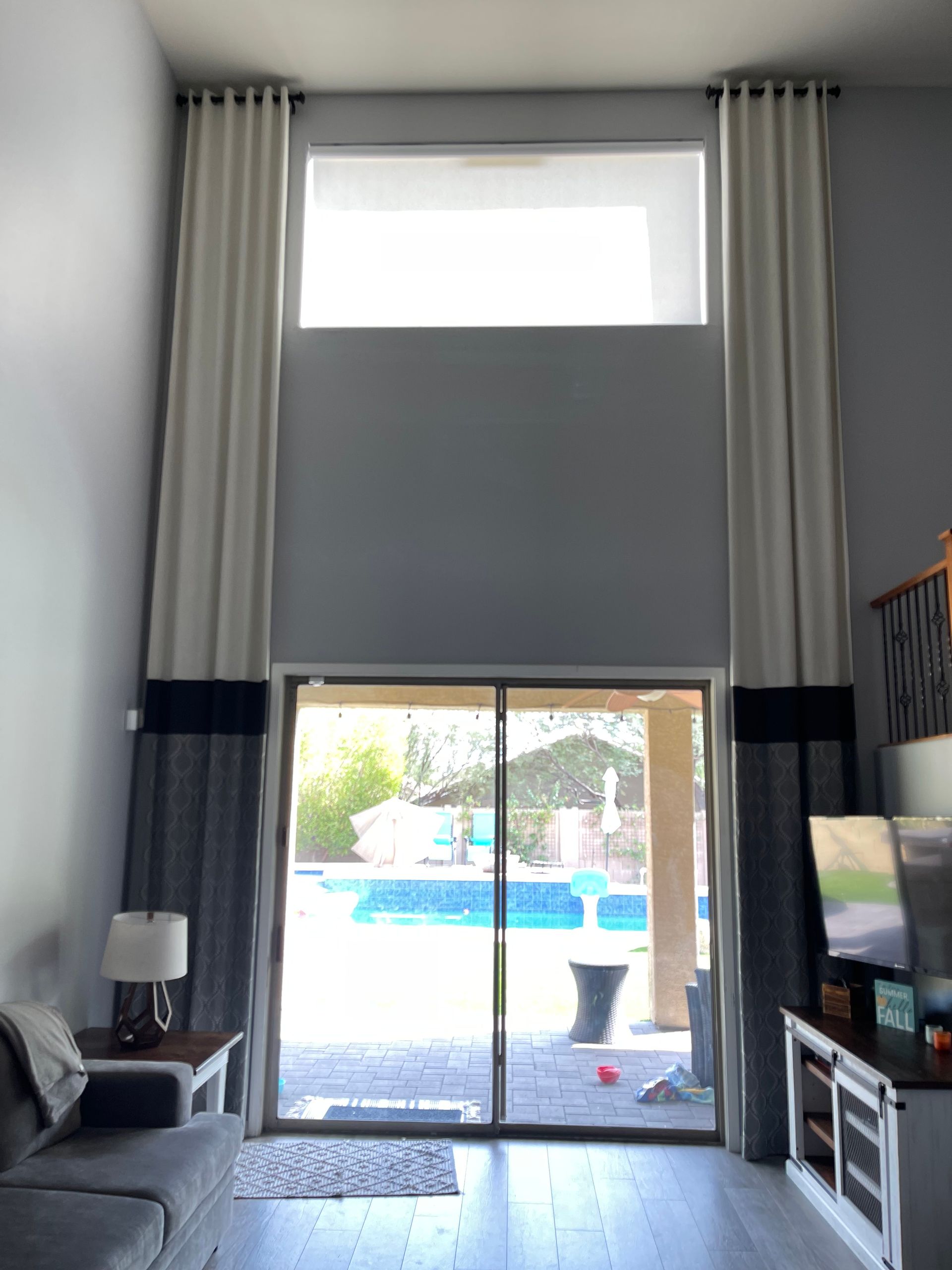 A living room with a sliding glass door leading to a pool the window is covered partly with blinds