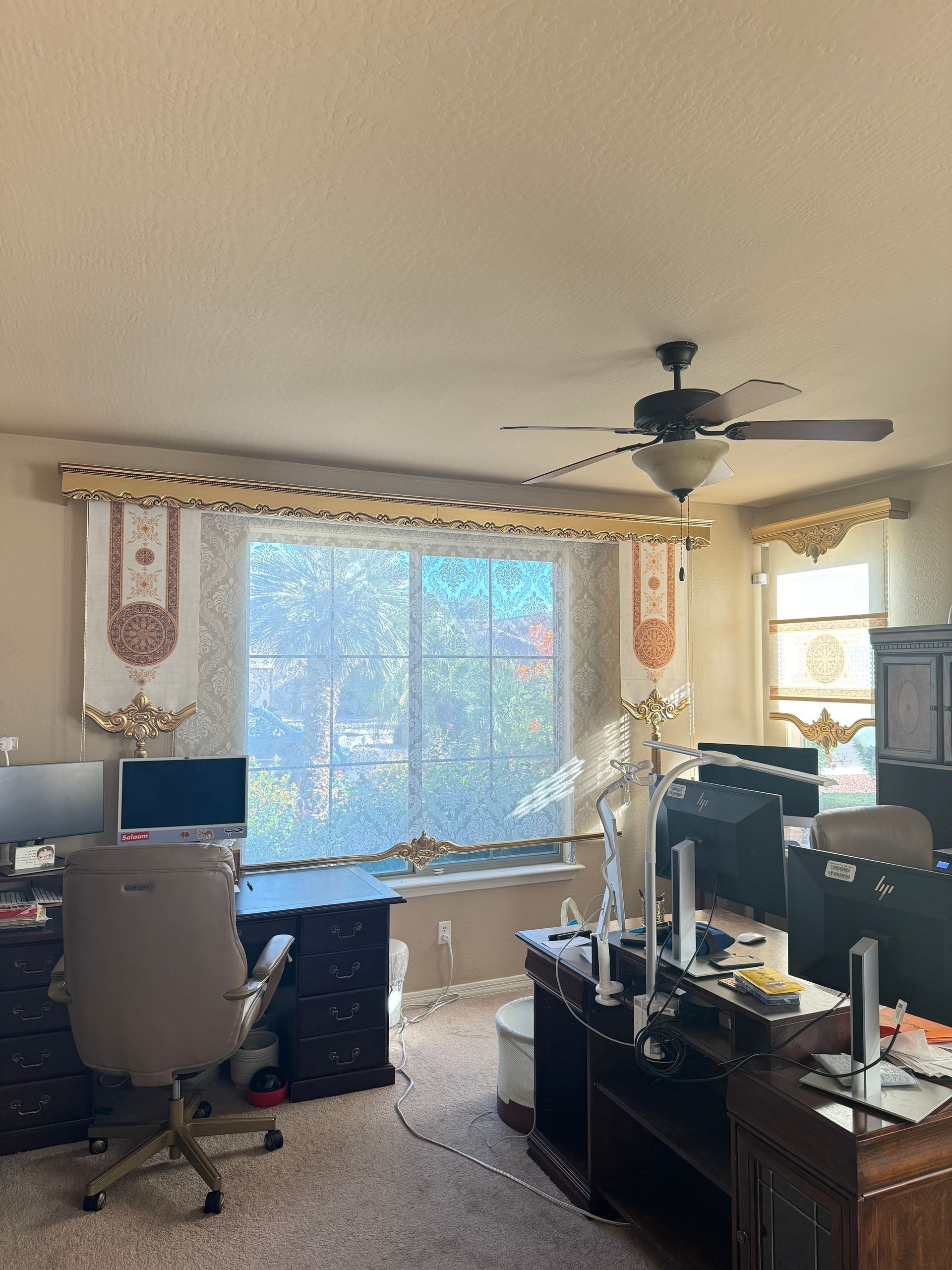 Gray sofas beneath gray blinds and decorative valances in a room with marble floors and a stone wall.
