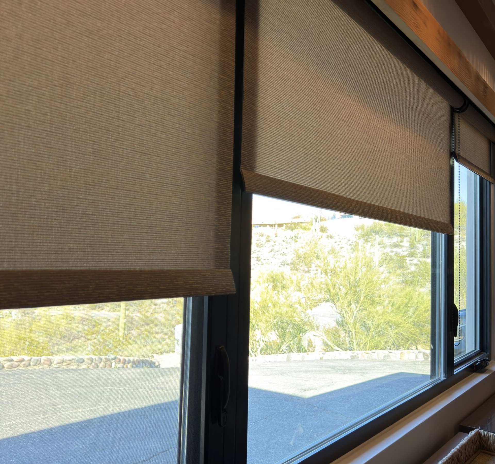 Tall windows with light curtains overlooking a backyard pool. A gray wall and TV are also visible.