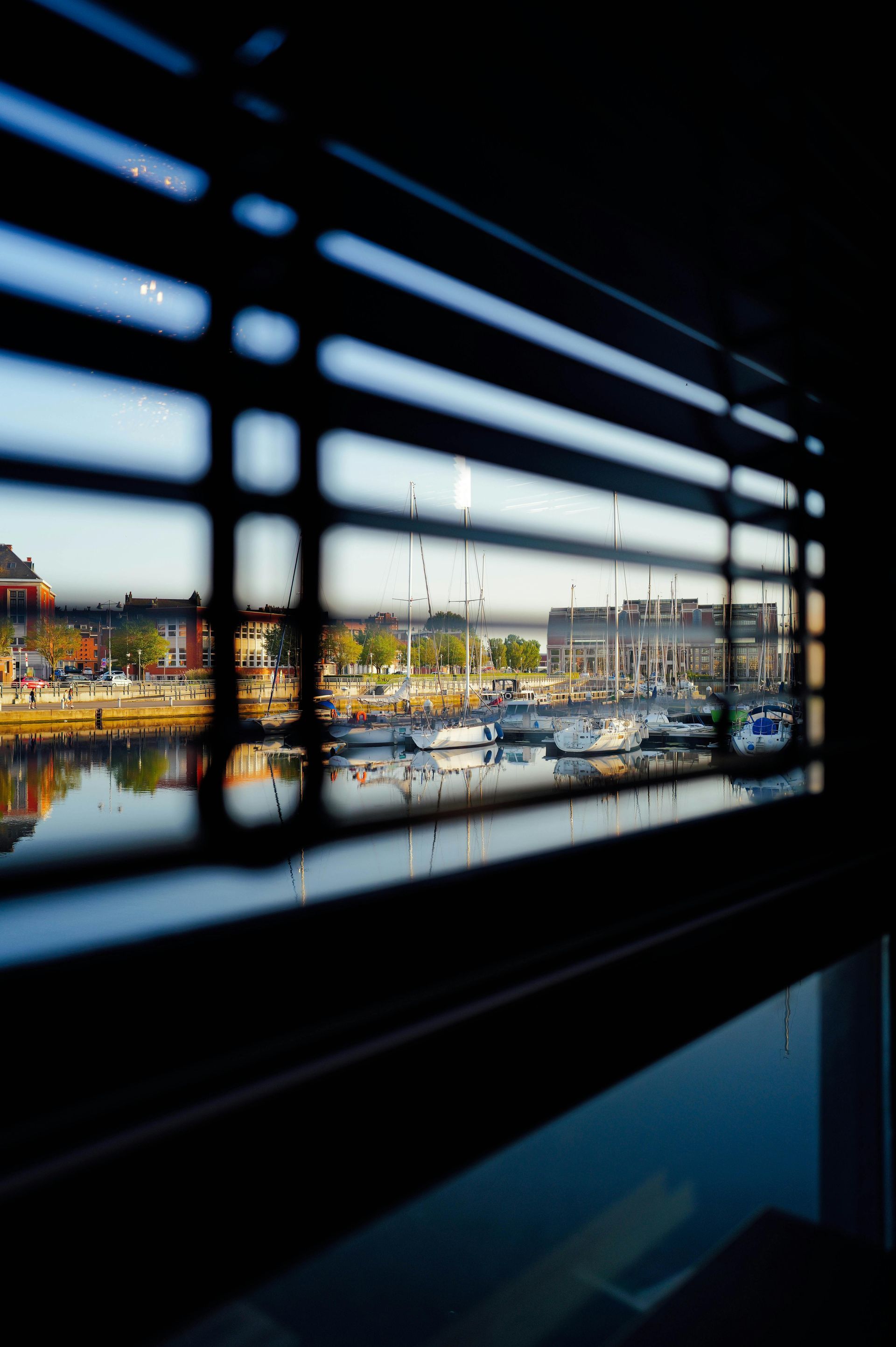 A view of a harbor through a window with blinds