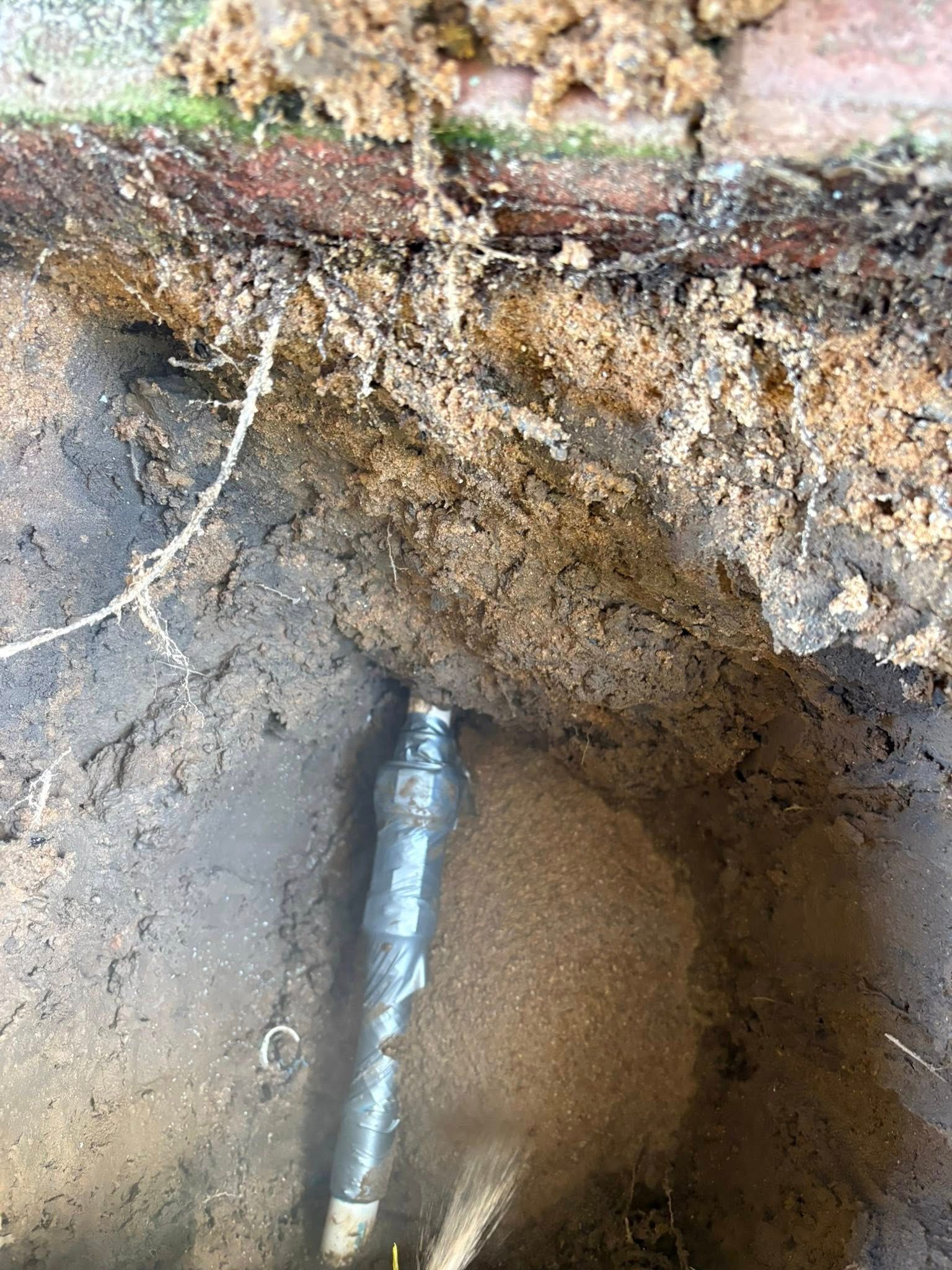 A pipe is coming out of the ground in a hole.