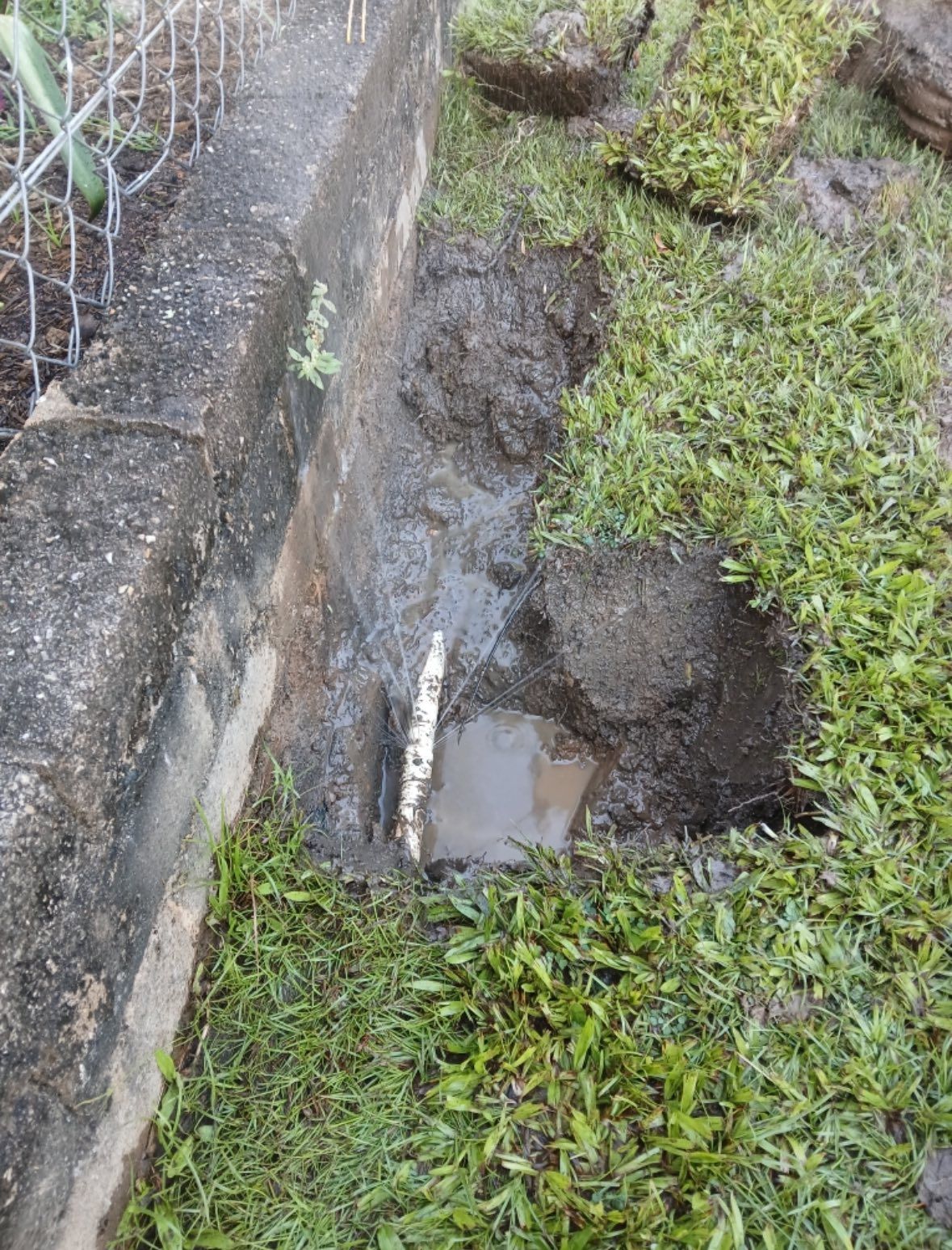 There is a hole in the ground with a pipe in it.