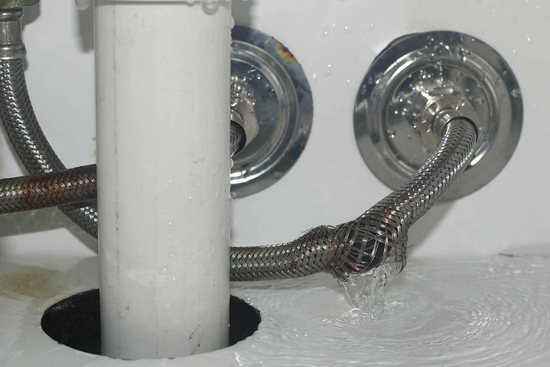 A hose is coming out of a hole in a sink