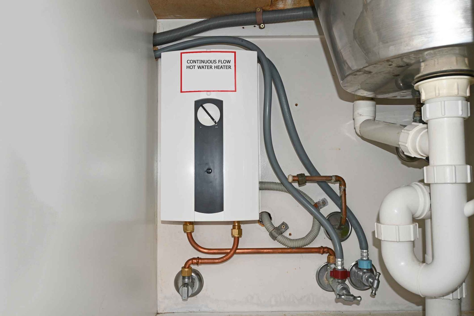 A water heater is installed under a sink in a kitchen