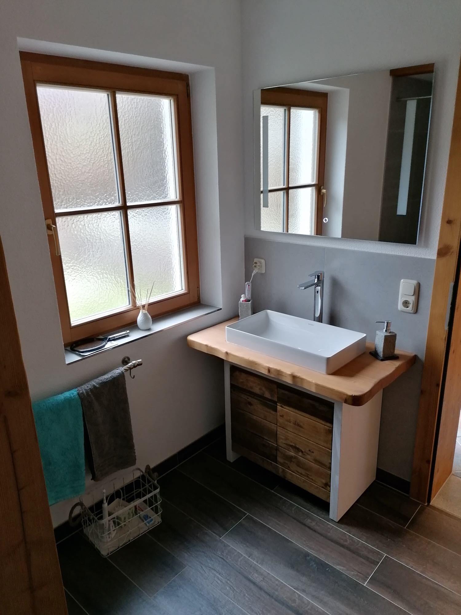 Badezimmer mit Waschbecken, Handtuchhalter, Spiegel und Armaturen