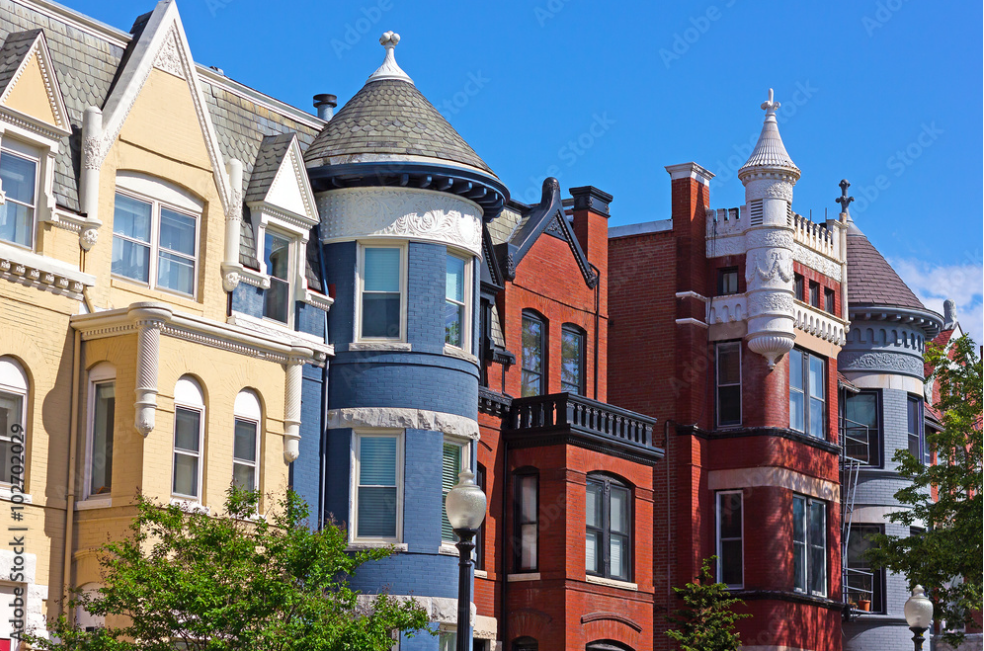 Row of colorful historic houses with bay windows and decorative trim.