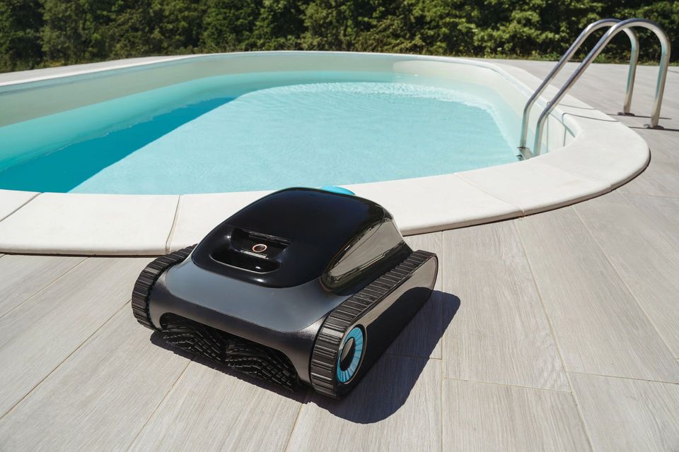 Robot per la pulizia della piscina accanto a una piscina turchese con bordo bianco e scaletta in metallo.