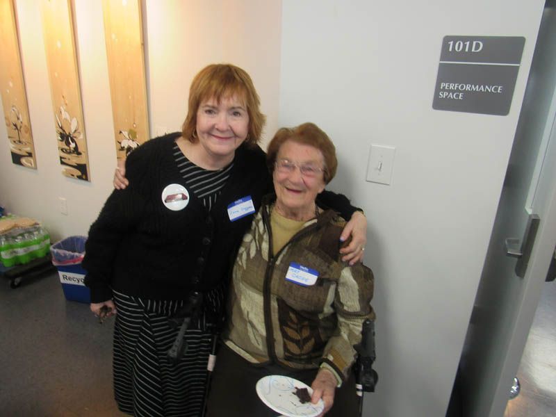 Two women are posing for a picture in front of a performance space sign.