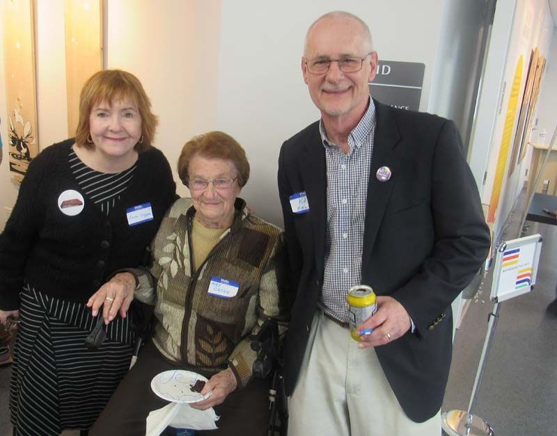 A man in a suit stands next to two women and a woman in a wheelchair