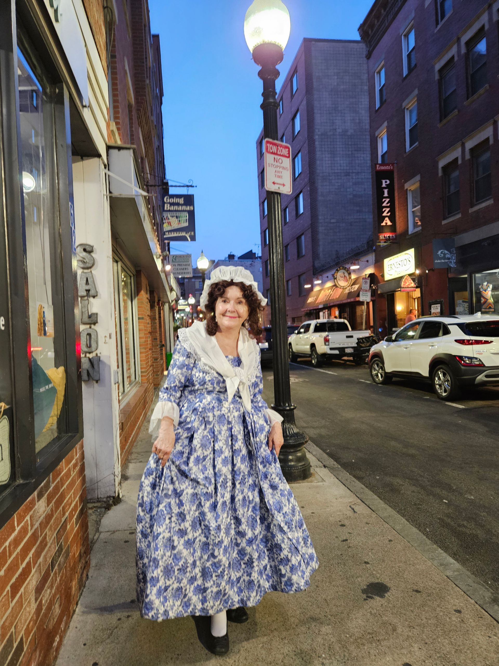 A woman in a blue and white dress is walking down a city street