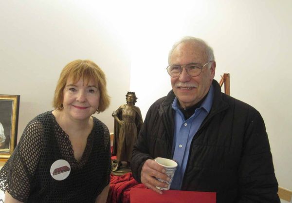 A man and a woman are posing for a picture in front of a statue.