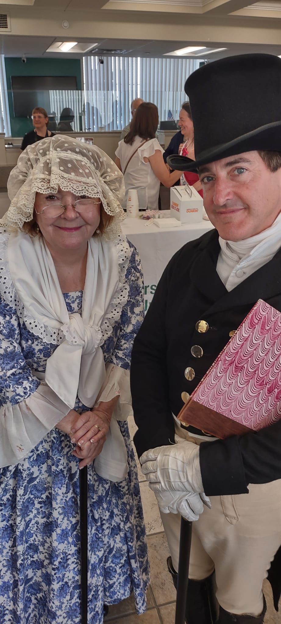 A man in a top hat and a woman in a blue and white dress are posing for a picture.