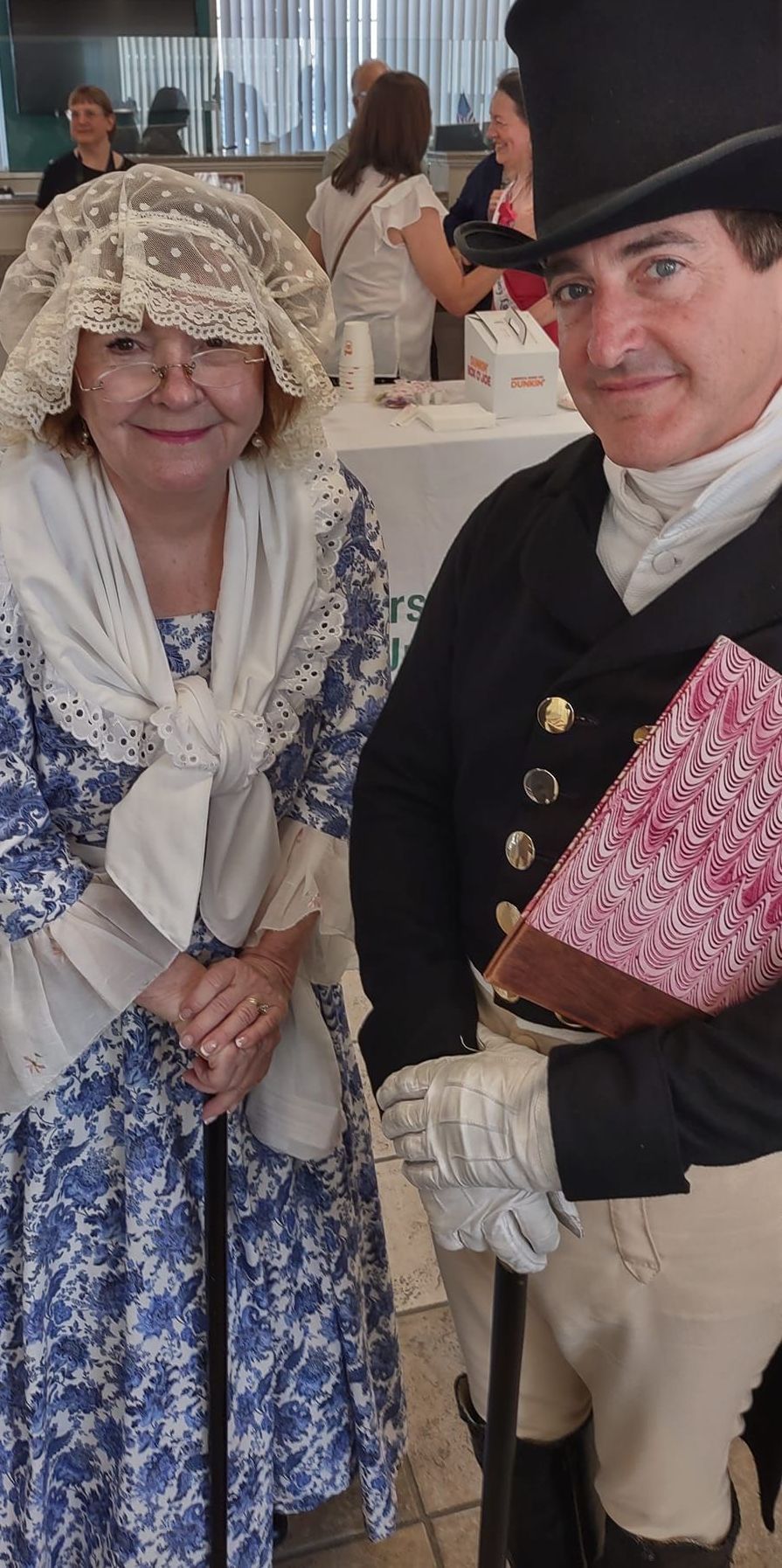 A man in a top hat and a woman in a blue dress are standing next to each other.