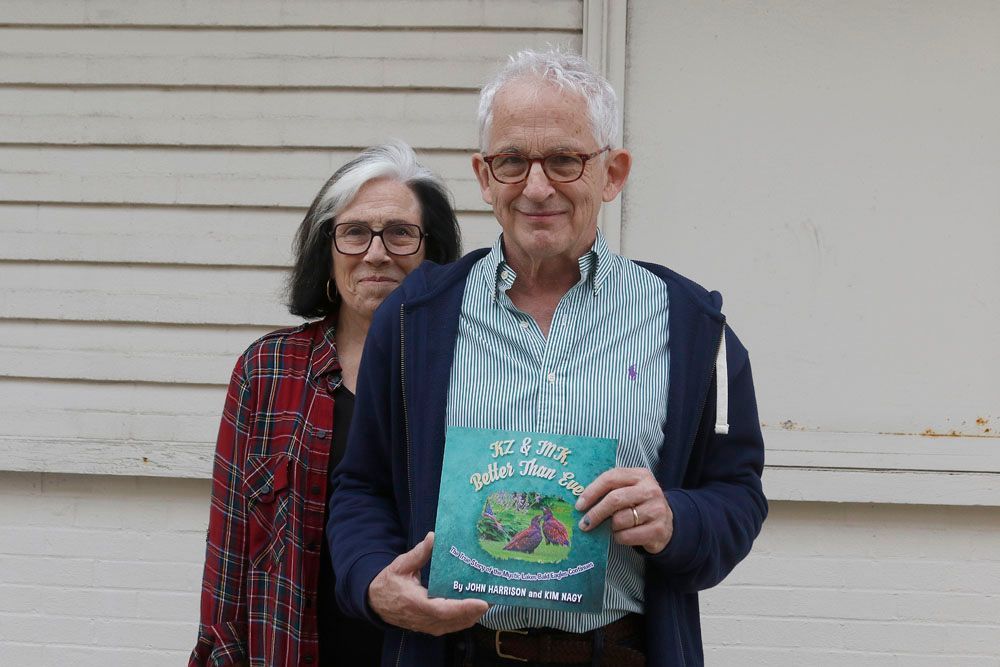 A man and a woman are standing next to each other holding a book.